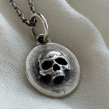 Silver necklace with a skull pendant on a light fabric background