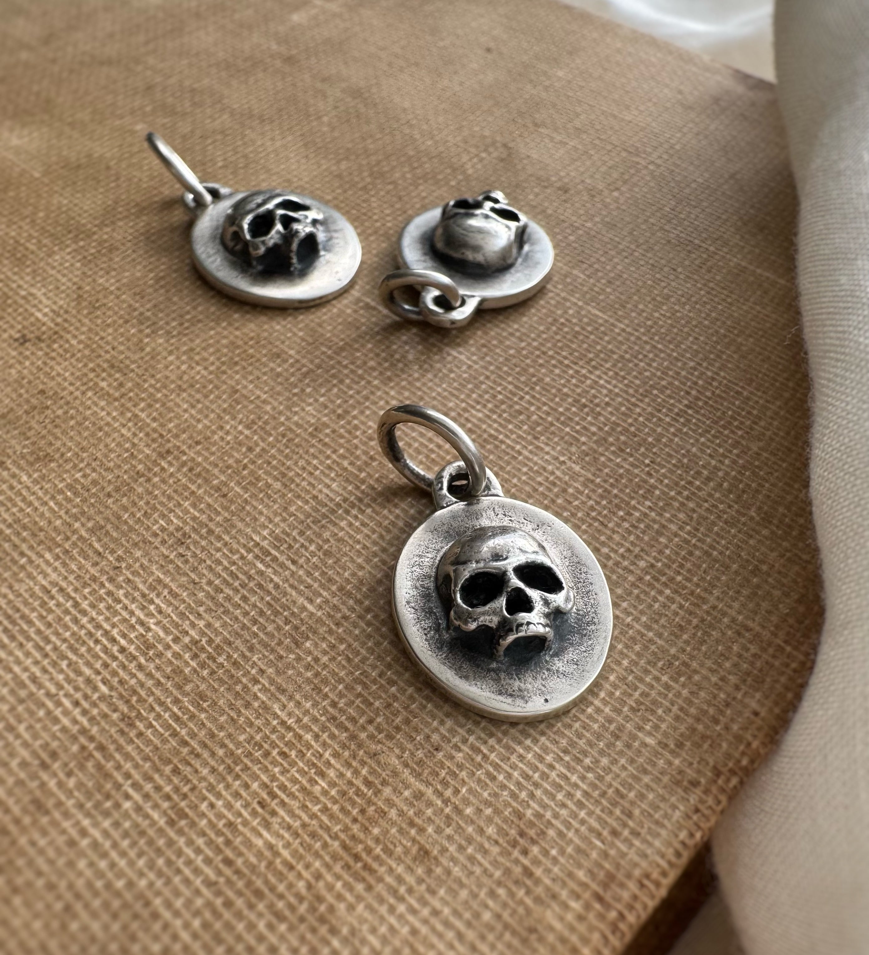 Silver skull pendant and earrings on a textured surface
