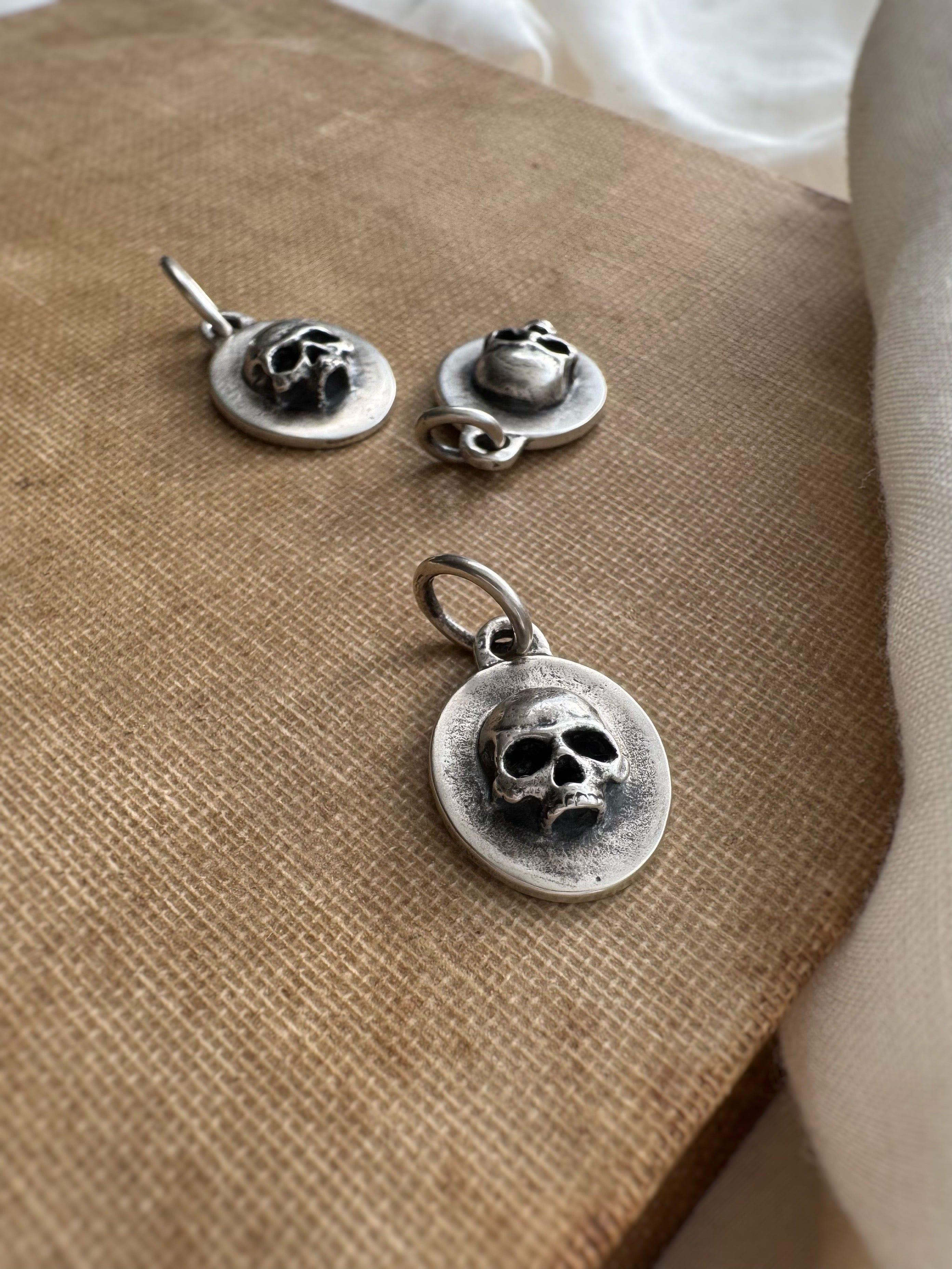 Silver skull pendant and earrings on a textured surface