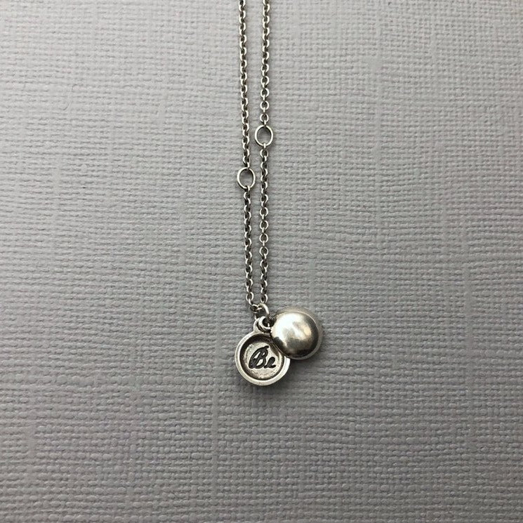 Meaning The tiniest locket, inscribed with the word "Be". To be; to inhabit or embrace a state of being. Invoke being at peace with yourself. Truly know, love, and accept your perfectly imperfect, delightfully authentic self. “To be yourself in a world that is constantly trying to make you something else is the greatest accomplishment.” ~ Ralph Waldo Emerson Details Locket measures approximately 1/4" in diameter. Hangs on a round cable chain Fastens with a lobster clasp