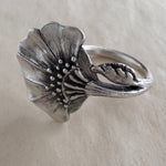 Silver floral ring on a cream background