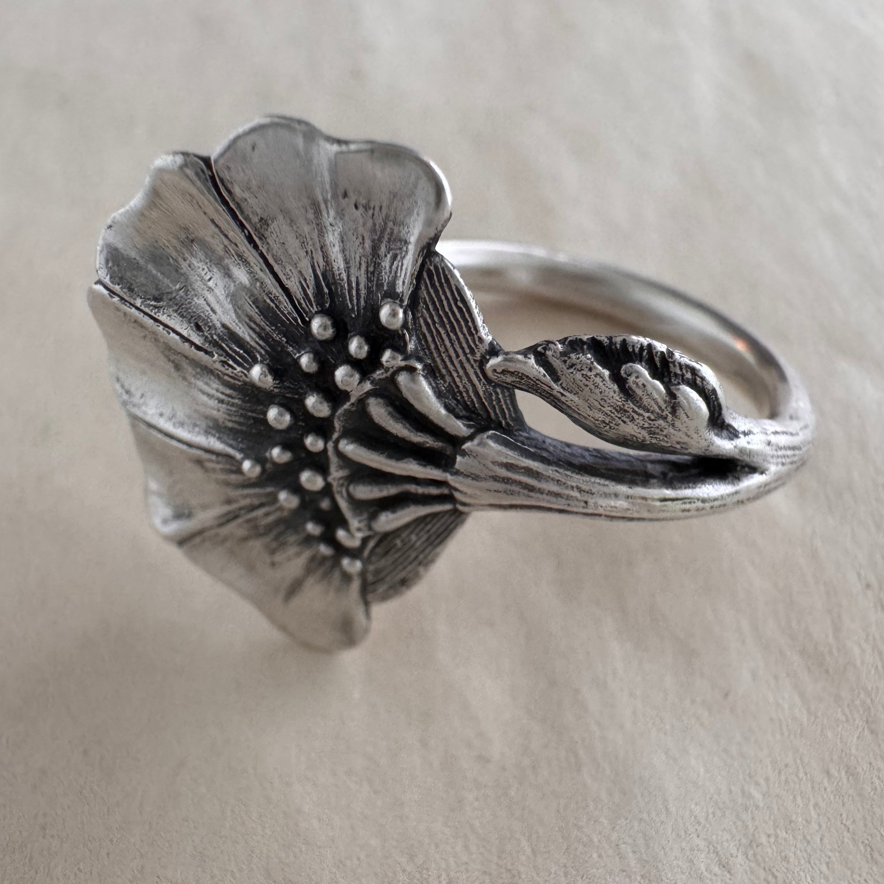 Silver floral ring on a cream background
