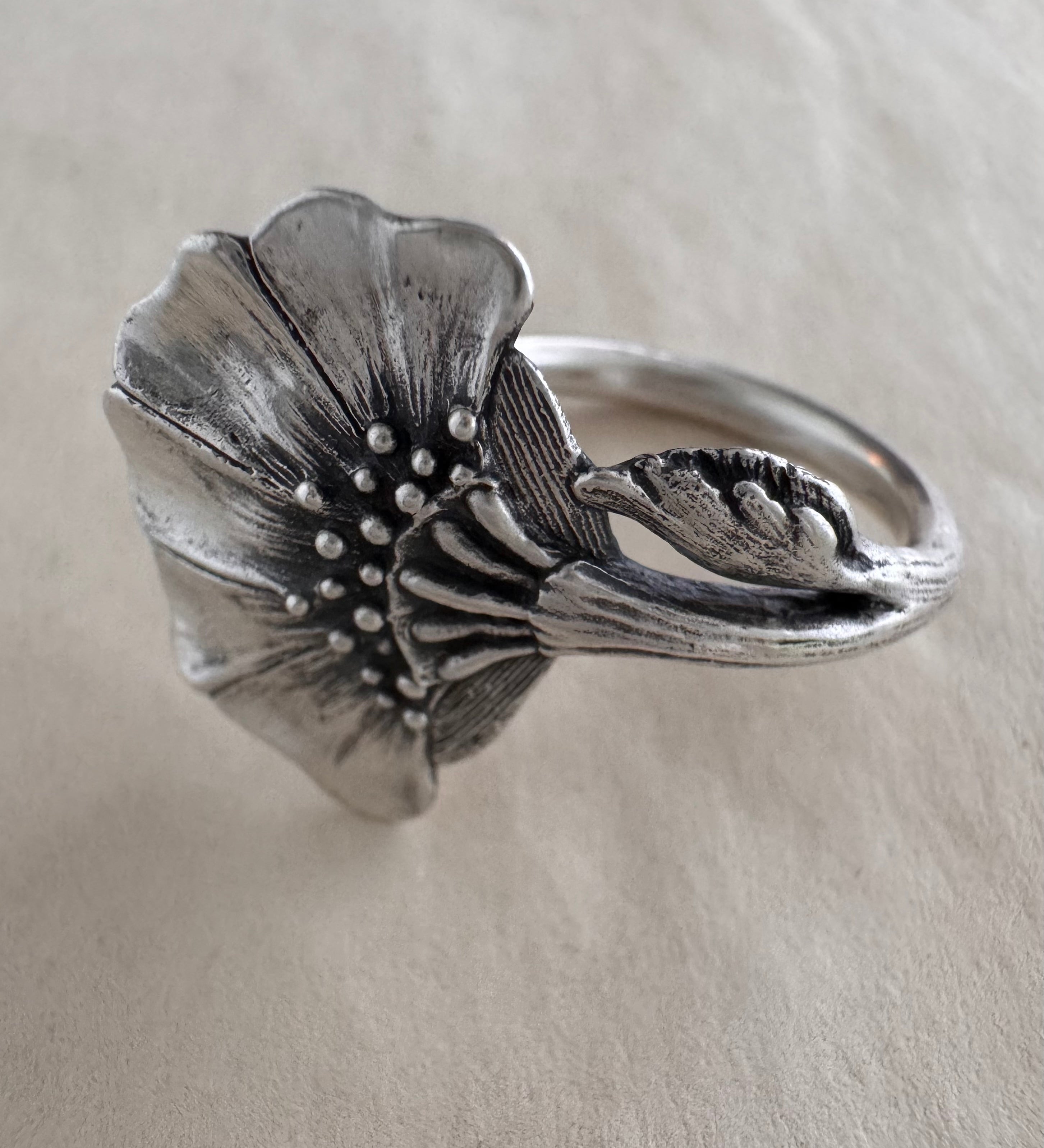 Silver floral ring on a cream background