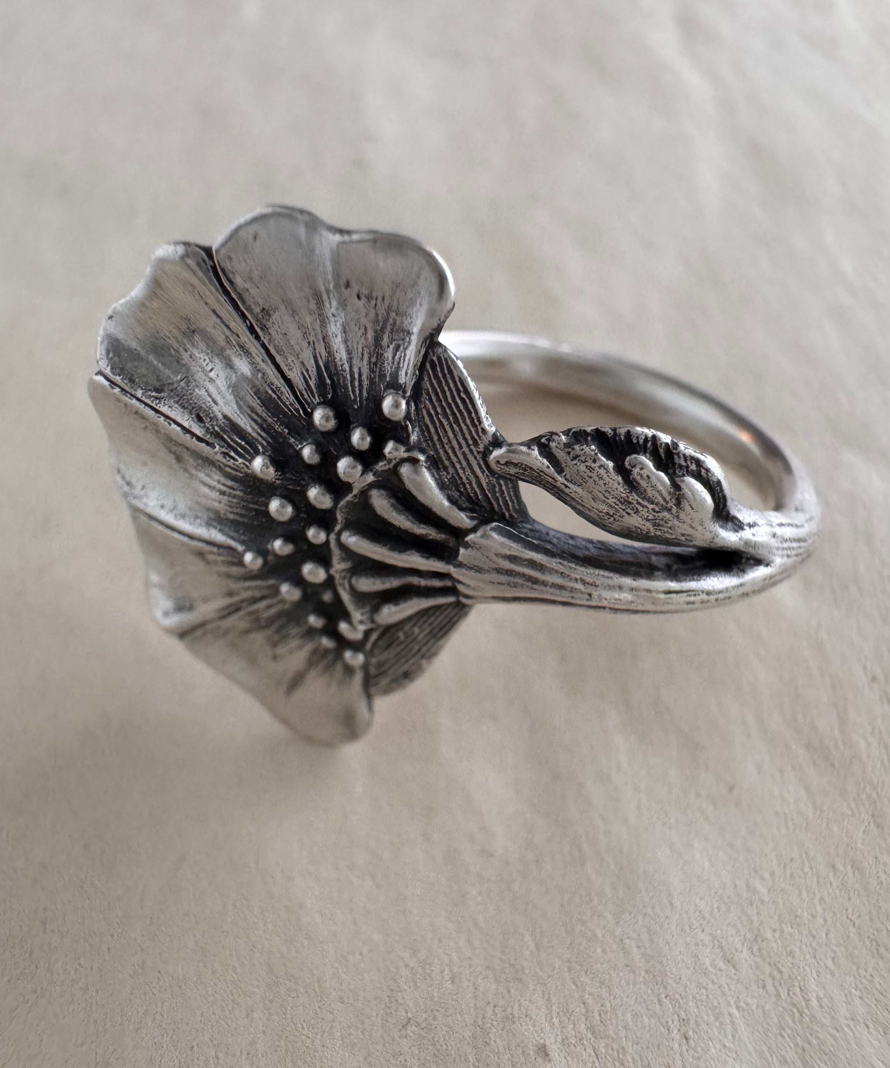 Silver floral ring on a cream background
