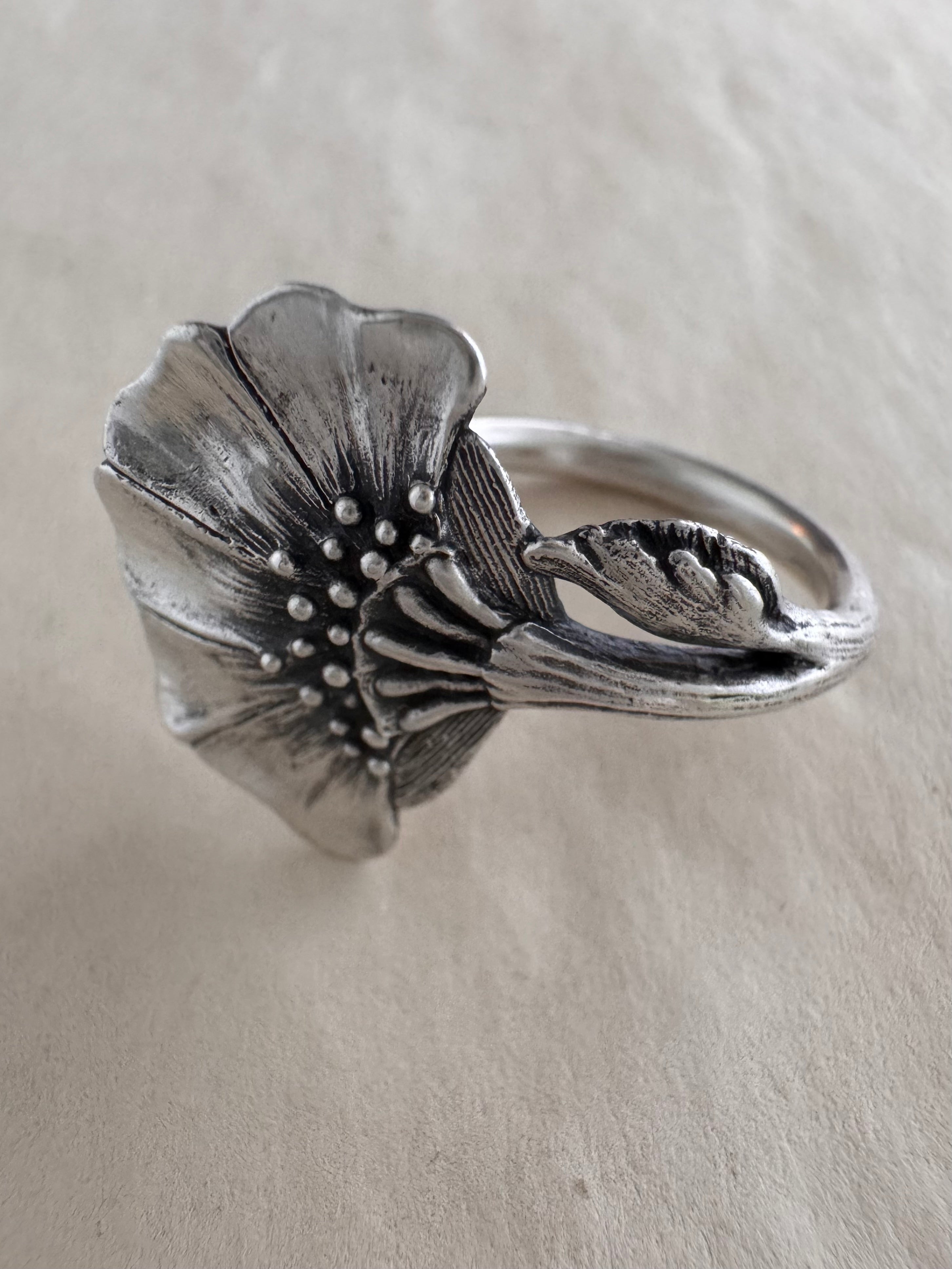 Silver floral ring on a cream background