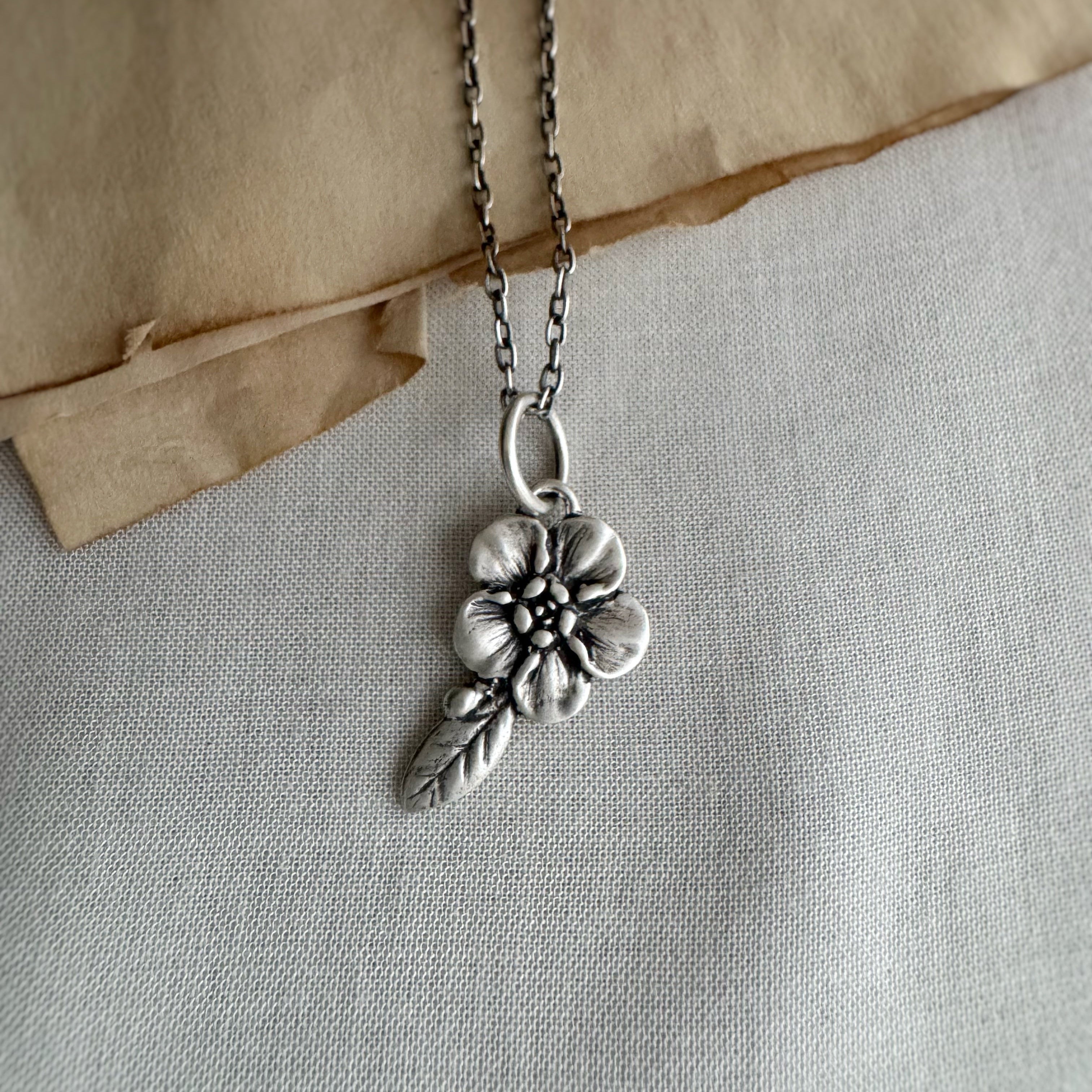 Forget Me Not Flower Charm, Sterling Silver on cream background