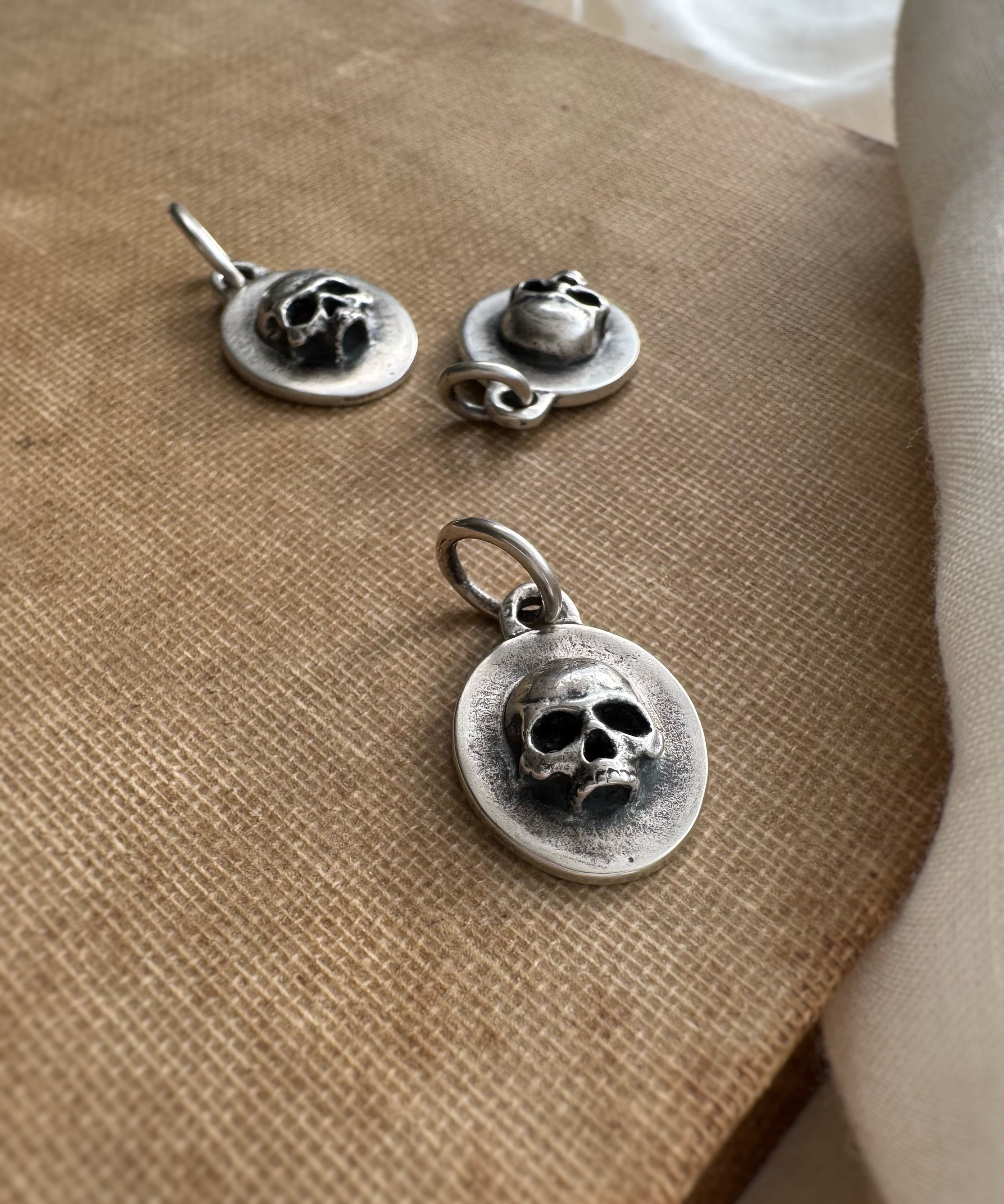 Silver skull pendant and earrings on a textured surface