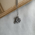Silver rose necklace on a light gray fabric background