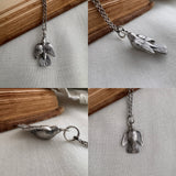 Collage of silver bird pendants on a chain against a neutral background. The  sparrow charm is shown from all angles, top, side view, and the belly of the bird.