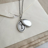 Silver handwriting locket with a pendant on a beige envelope