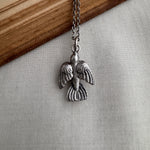 Silver sparrow pendant necklace on a chain against a neutral background