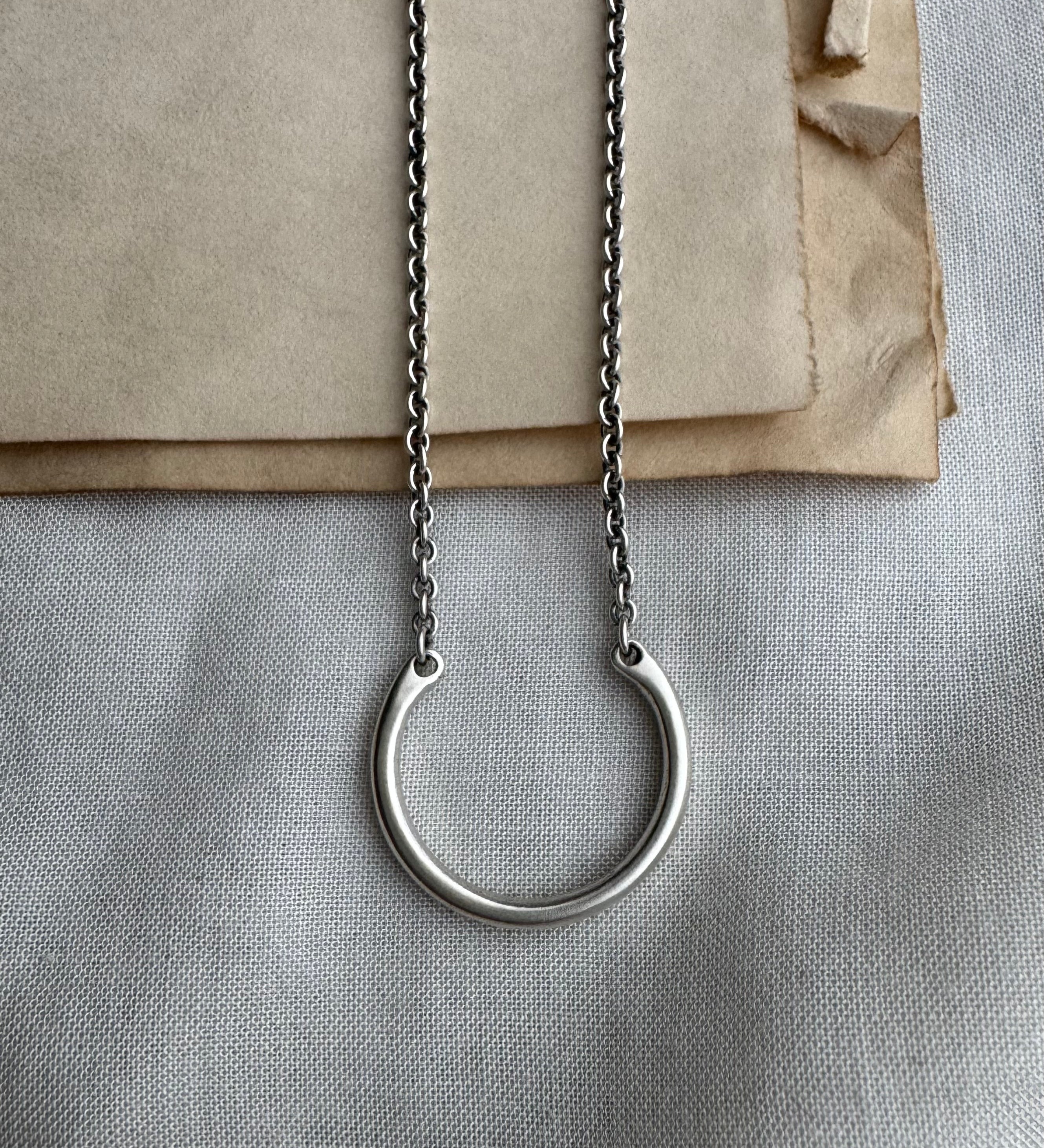 Silver necklace with a circular pendant on a textured surface