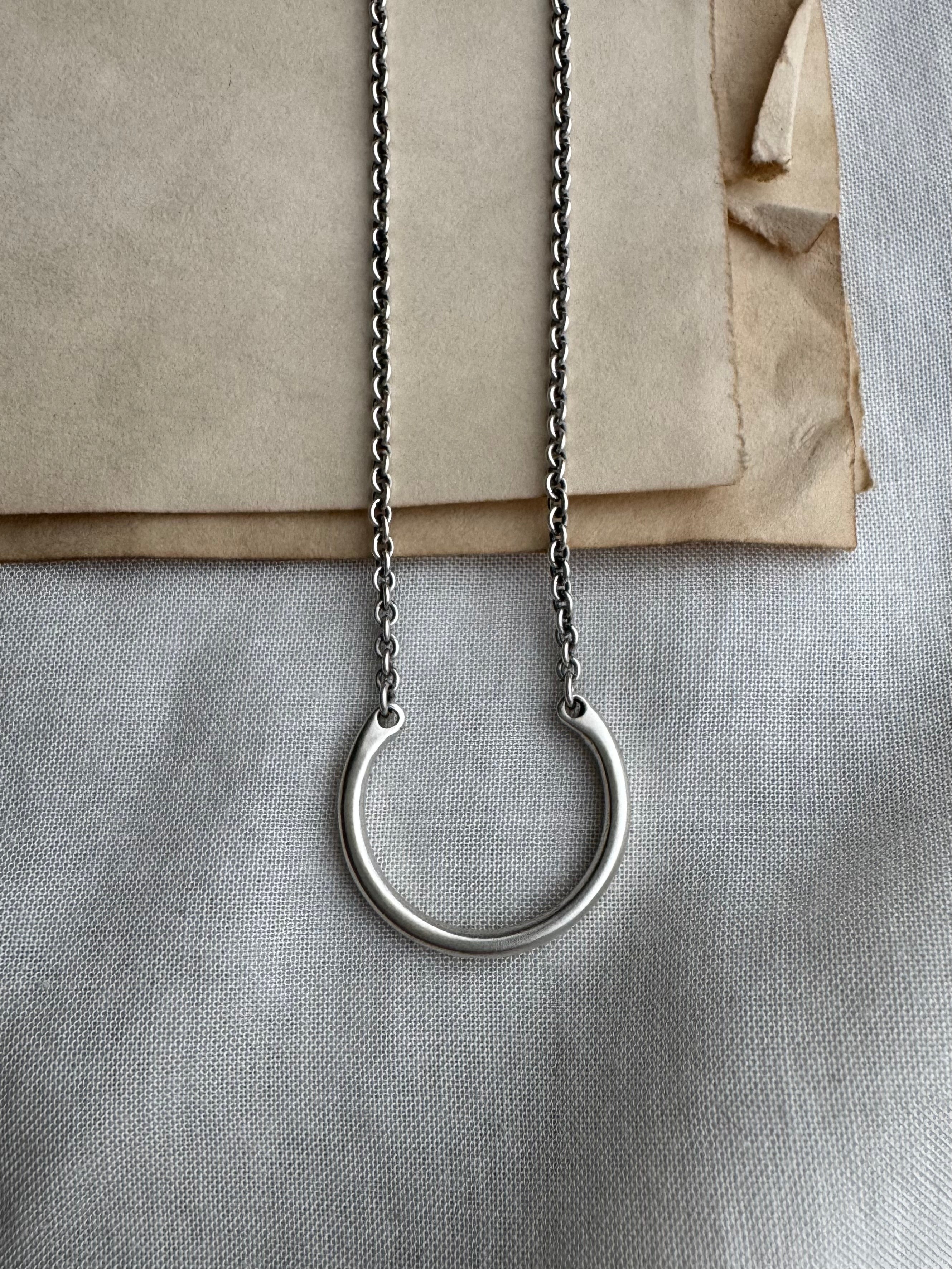 Silver necklace with a circular pendant on a textured surface