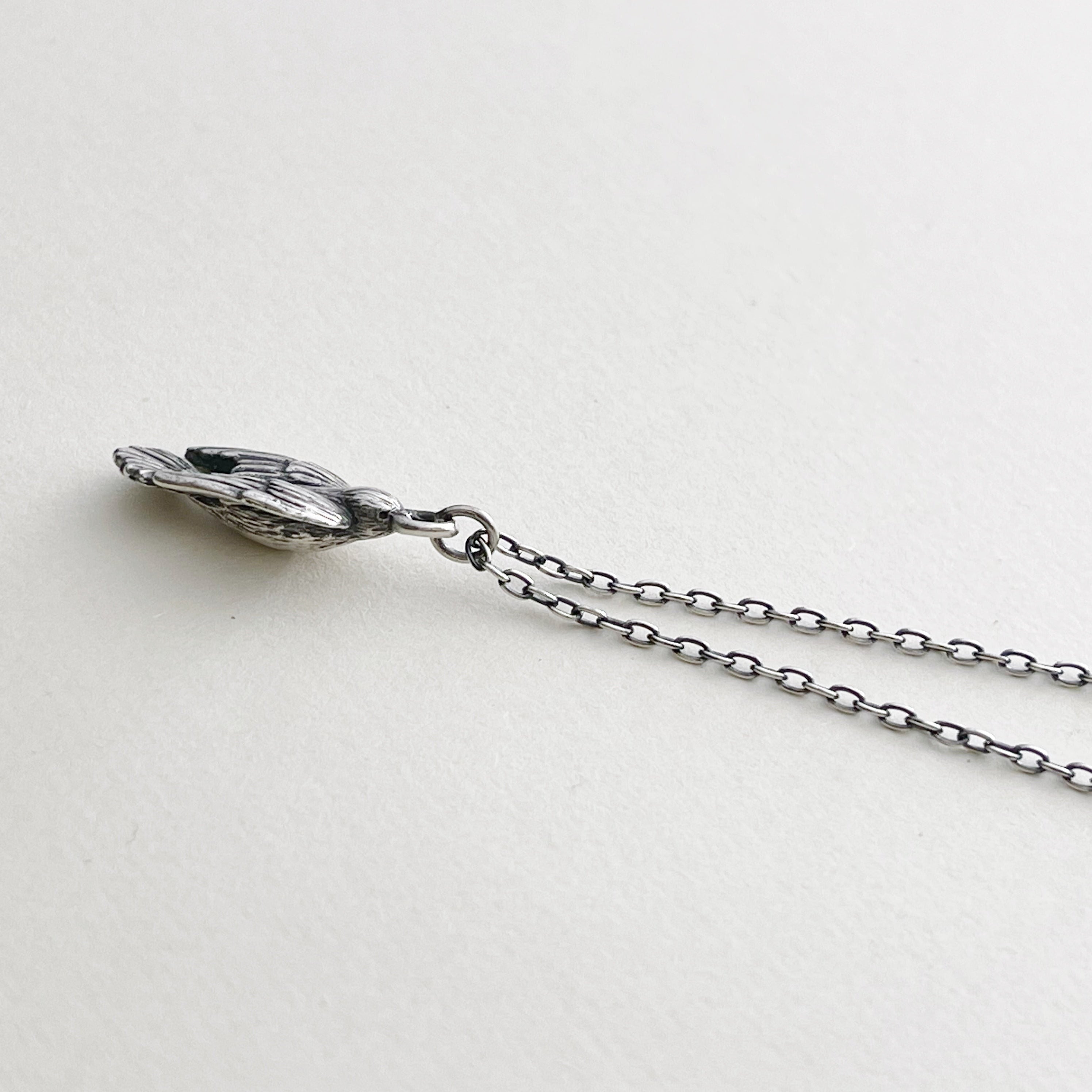 Sterling silver charm necklace, bird is in flight on cream background