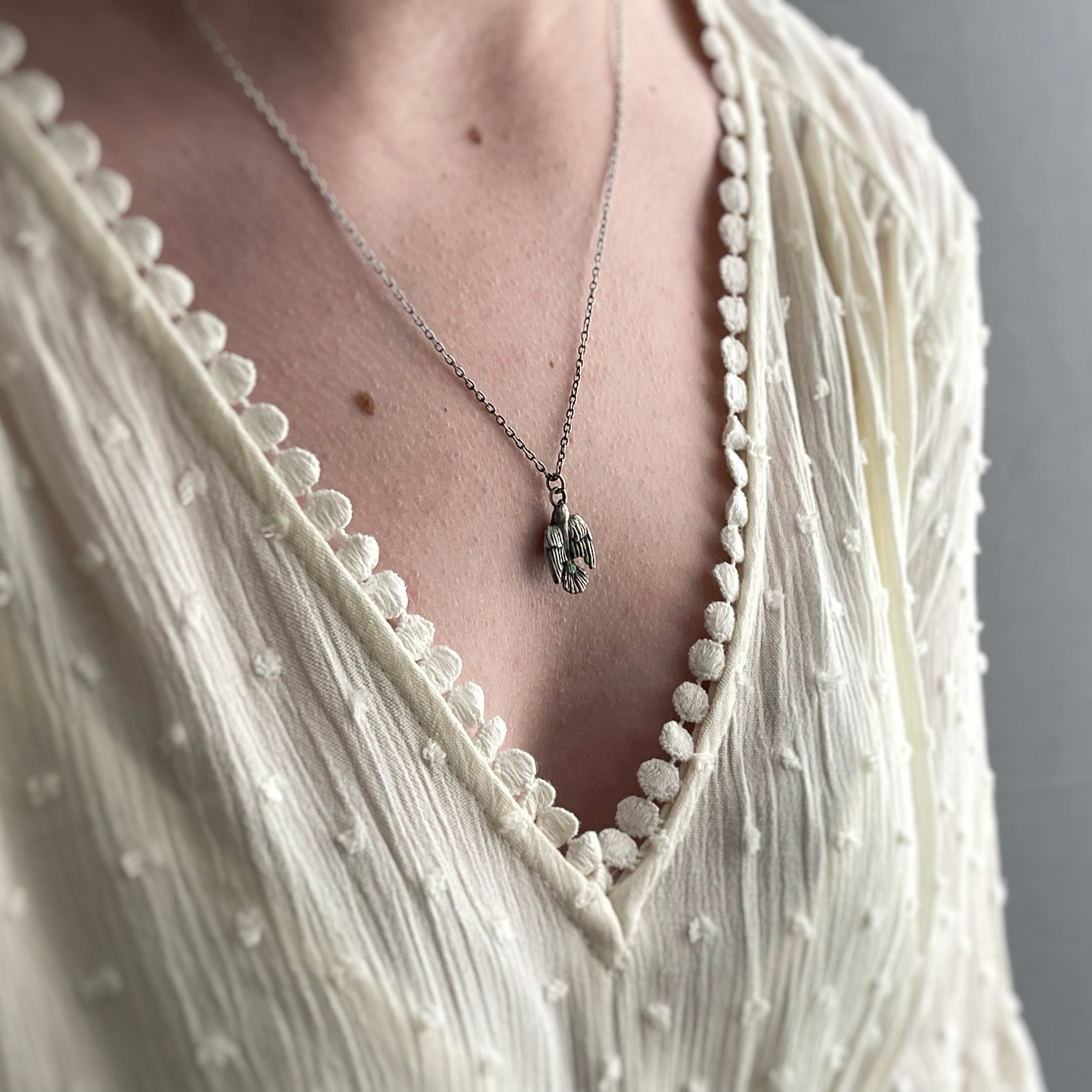 sterling silver sparrow necklace worn on model with white dress